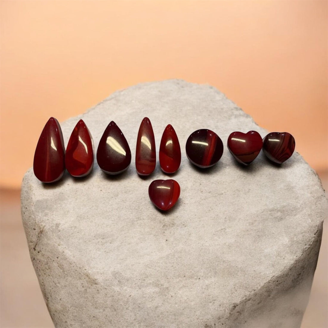 Collection of deep red Rosarita cabochons in pear, oval and heart shapes, handcrafted from rare gold slag material used in artisan jewellery making.